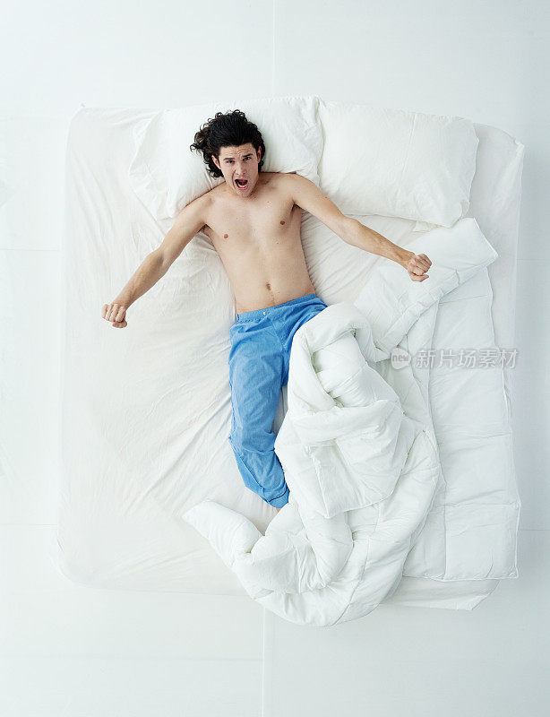 全身/只有一个男人/直接俯瞰20-29岁英俊的人/长发白人男性躺下/打盹/睡觉/放松/休息/醒来在卧室的白色背景下穿着裤子/睡衣